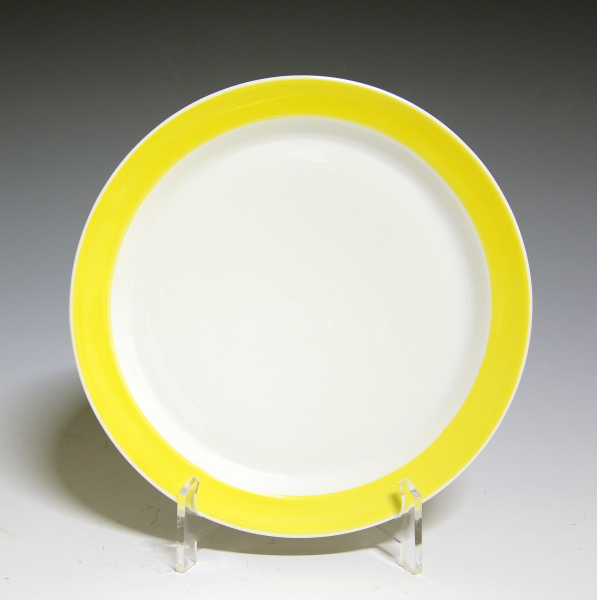 Asjett av porselen. Hvit med gult bånd rundt fanen.

Modell: Style, formgitt av Poul Jensen.