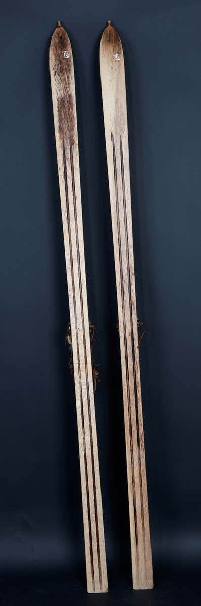 Ski ett par av hickory med oppbøyet budt spisst horn. Oversiden flat med 6 strekmåtstriper. Tverr bak. Huitfeldtbinninger.