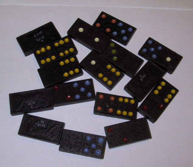 Dominospill med svarte brikker dekorert med en tiger på baksiden. Forsiden har ulike farger for de ulike verdiene (antall prikker).