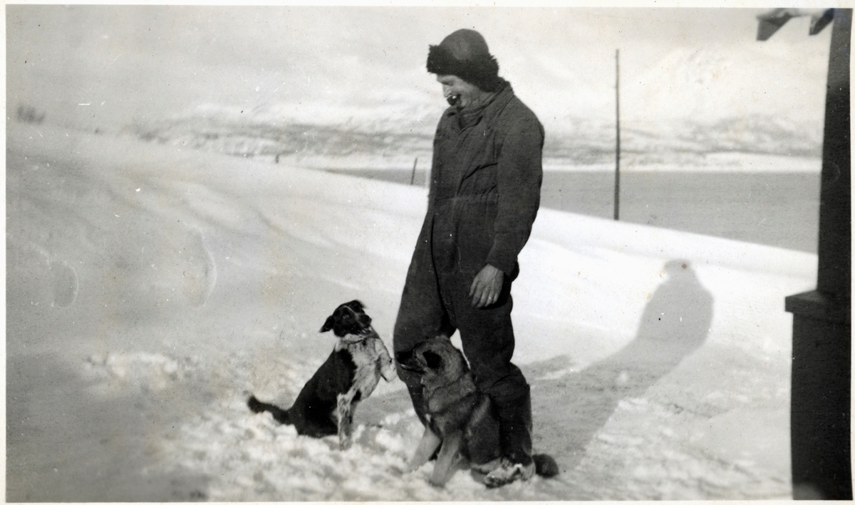 Wilhelm Rogde, fotografert utendørs med pipe og to hunder.