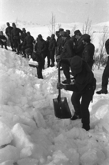 To befalsskoleelever graver i snøskavel, resten av troppen følger med.