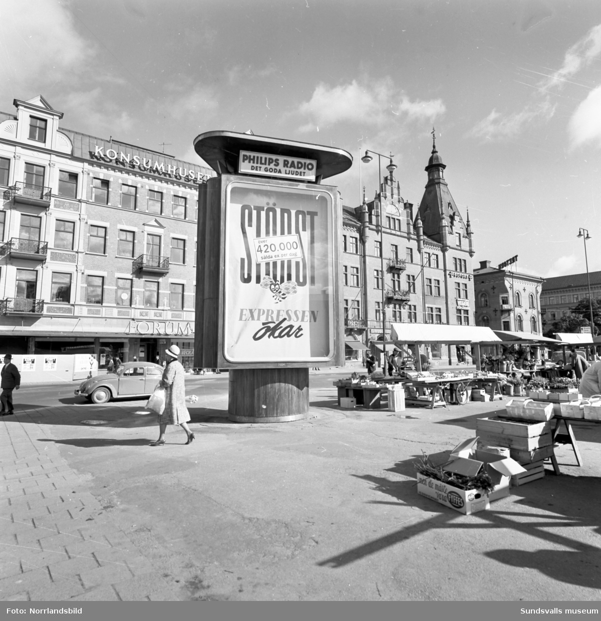 Stora torgets nordvästra hörn. På reklampelaren framför Forumhuset, den så kallade "Luffarbion", presenteras Expressens ökande upplaga.