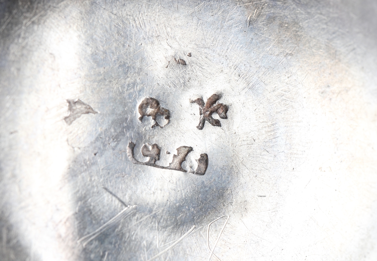 Tumlare, tillverkad av tunt silver. 
Halvklotformad. Den har utvikt mynningskant med en graverad våglinje under. 
Stämplar (mycket svårlästa) i botten.

Inskrivet i huvudbok 1876.
