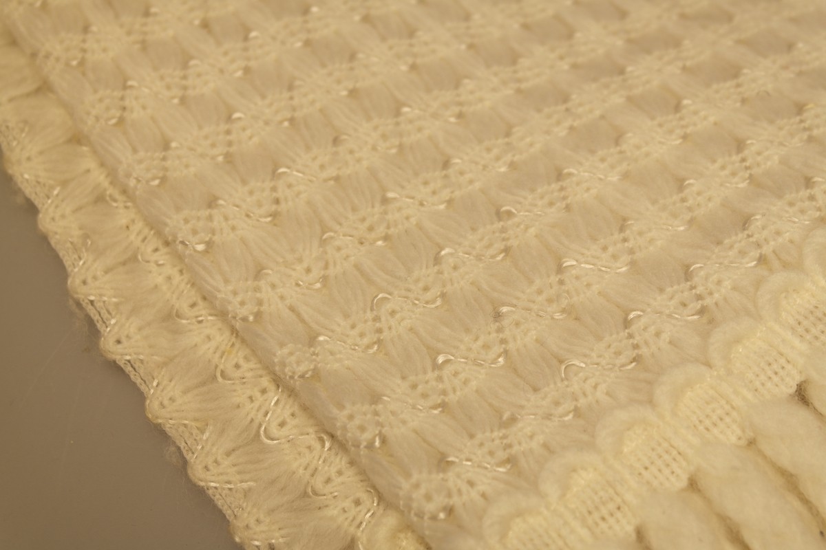 Offwhite sjal med frynser. Sjalet har ifelt silkeliknende tråd som del av mønsteret.