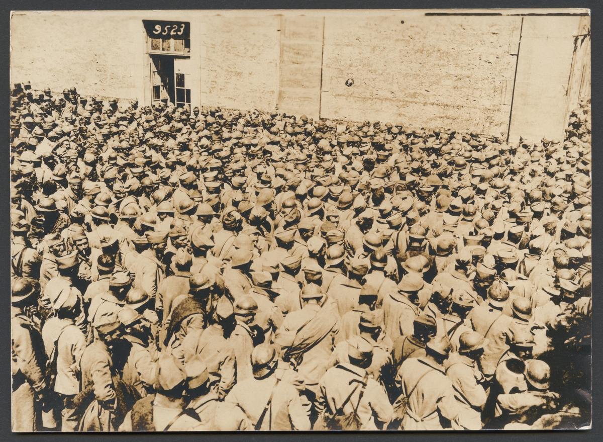 Bilden visar en stor mängd krigsfångar framför en stor vägg.