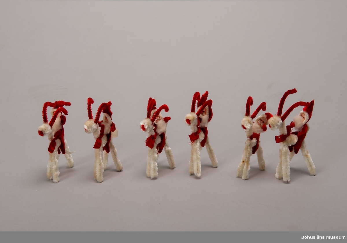 Tomte av röda piprensare, ridande på bock av vita och röda piprensare, sex sycken.
UM015961:001 - UM015961:006, de tre första är märkta.
Se UM015810