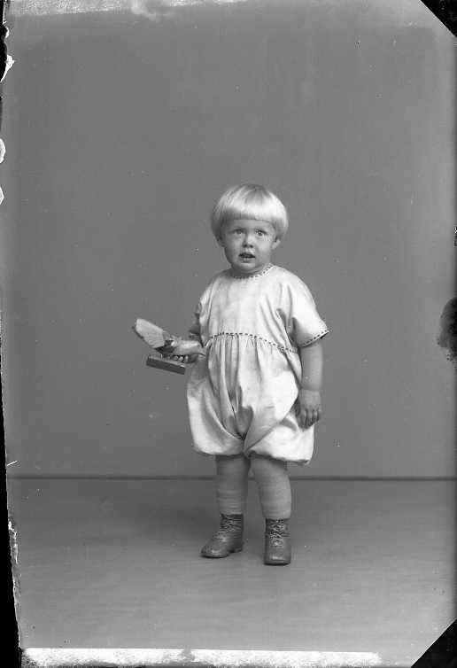 "Gossen Rahm", en liten ljushårig pojke som håller en träfågel i handen.