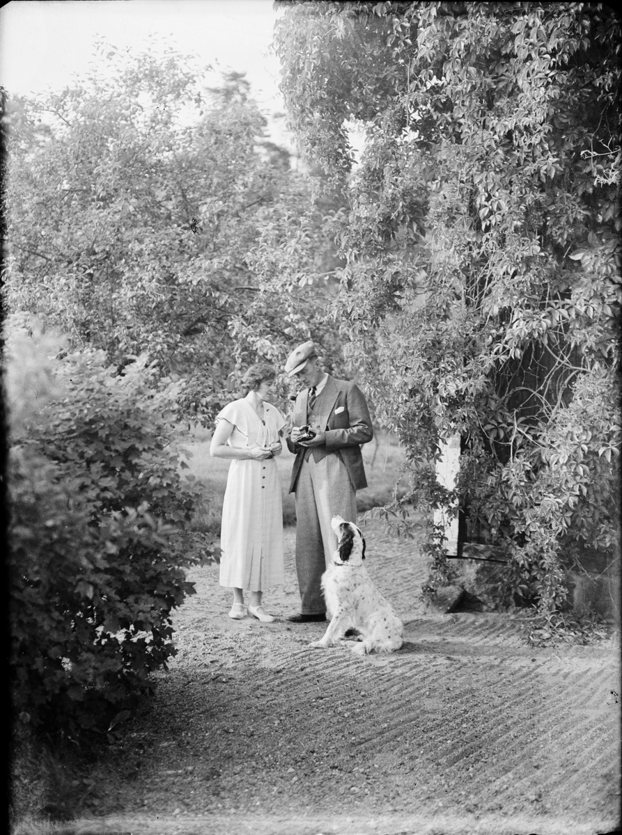 Holger Nelander tillsammans Ester och hunden Mussi i trädgården, Parkudden, Harg socken, Uppland