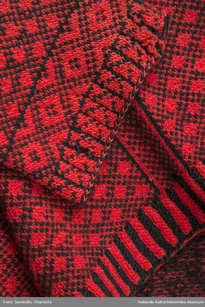 Bingetröja stickat av rött yllegarn med mönster i svart garn. I halsen 1 knapp, därunder "FES 1915". Hål vid höger ärmhåla.