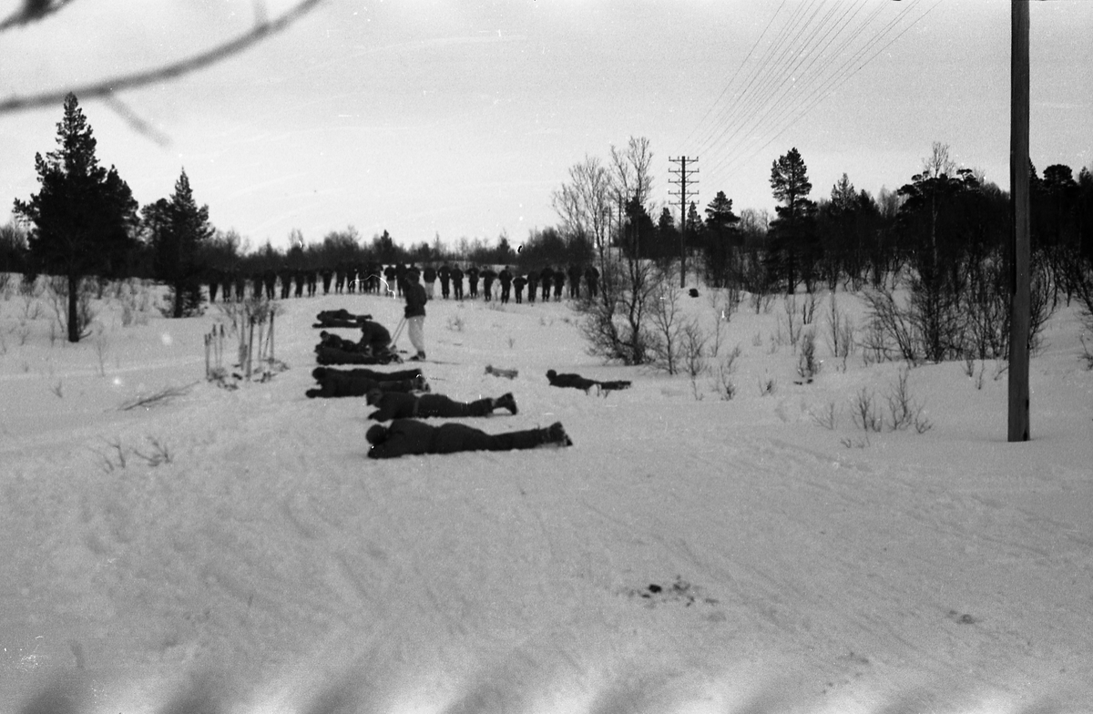 Avfotografert bilde av uidentifisert militært personell på ski under øvelse/instruksjon i vinterterreng på ukjent sted.