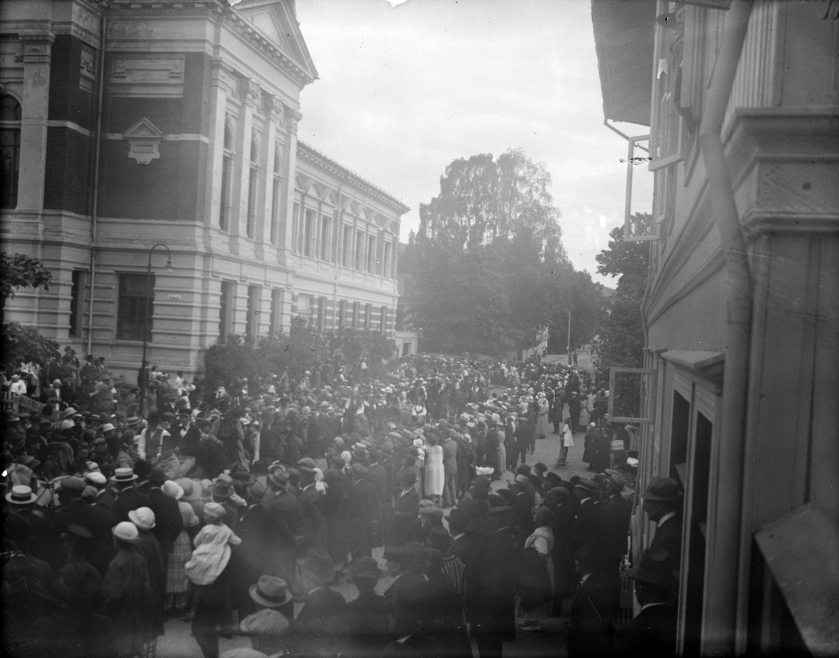Stor menneskesamling utenfor Kulturhuset Banken (1894), Lillehammer Sparebank holdt hus der til 1964.  Antagelig et opptog til eller fra Maihaugen.
