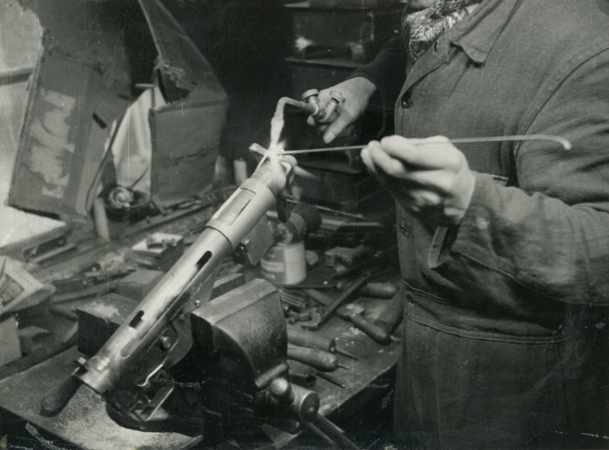 Motiv av mann som står å lodder på et Stengun våpen brukt under 2. verdenskrig.