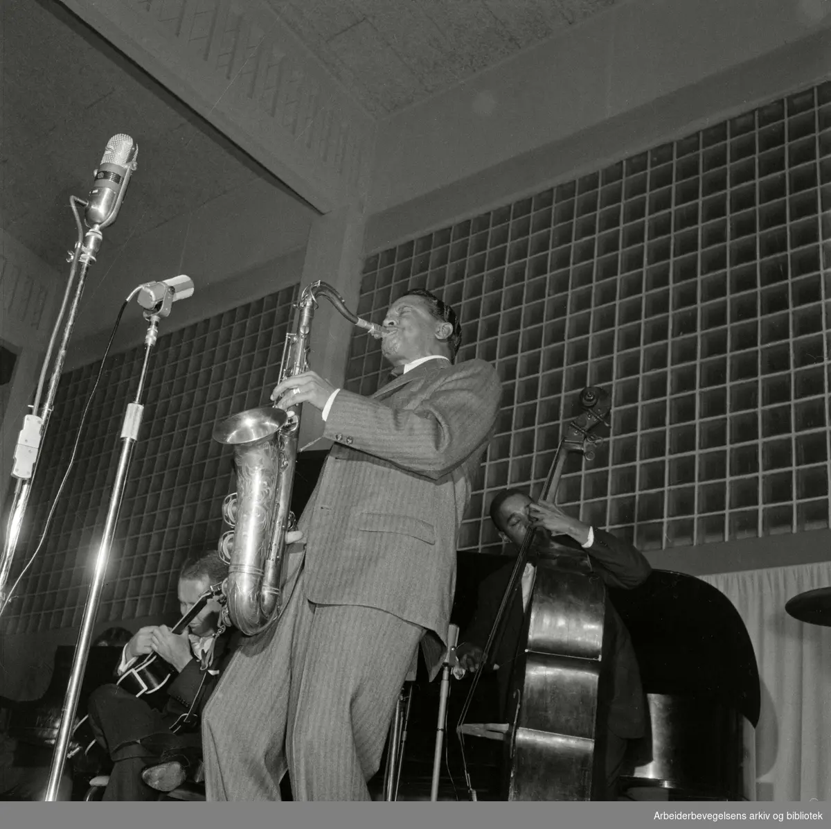 Jazz at the Philharmonic besøker Oslo februar 1956. Konsert i Nordstrandshallen. Fra venstre: gitarist Herb Ellis, Illinois Jacquet på tenorsaksofon og Ray Brown på bass.
