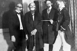 Gruppeportrett av fire menn utkledd i kostymer og med løsskj