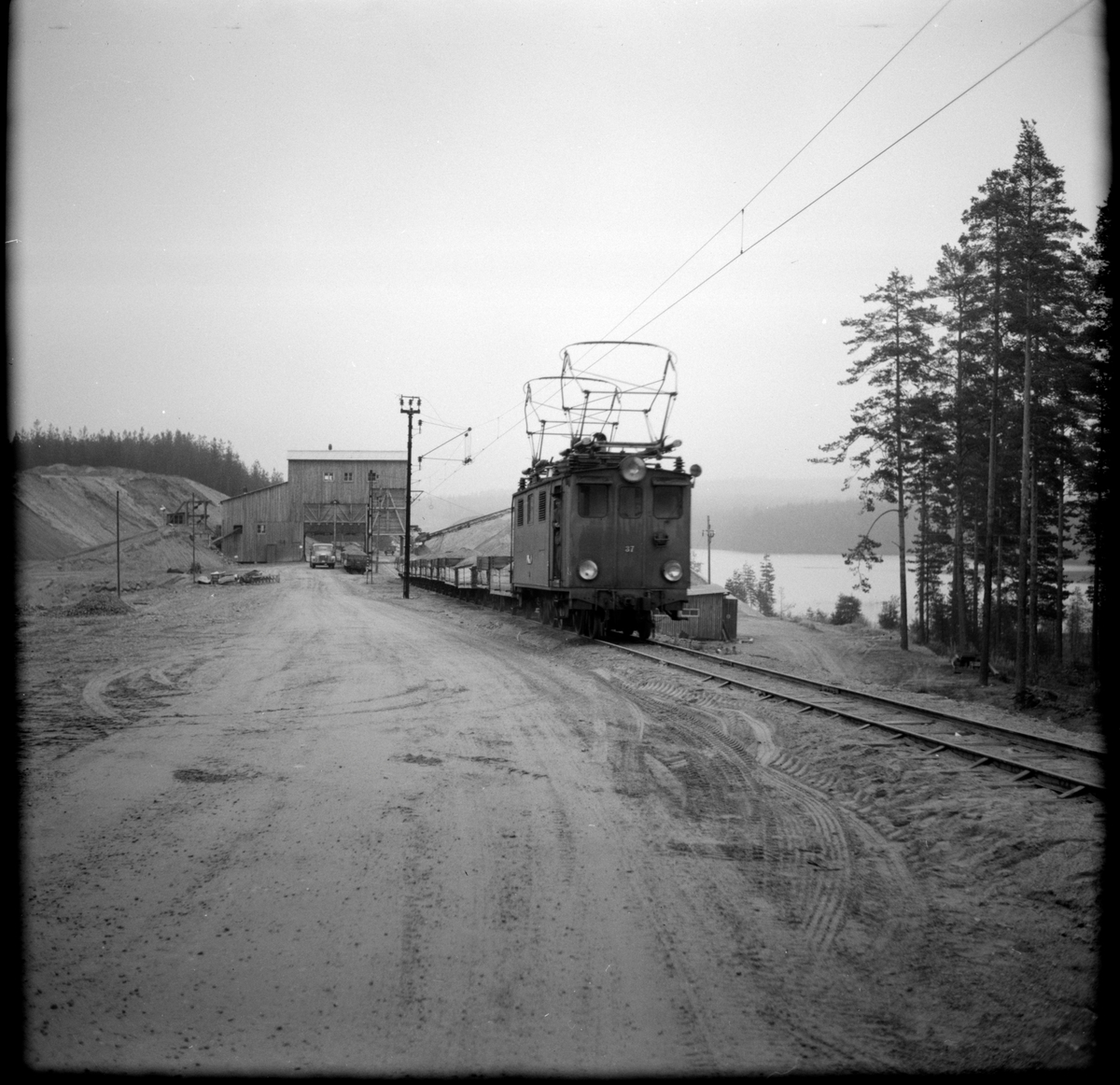 Vid grustaget ses Nordmark - Klarälvens Järnväg, NKlJ ellok 37 med fyra godsvagnar.