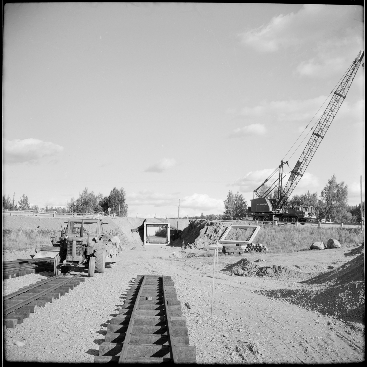 Pågående arbete med hjälp av kranbil och traktor vid läggning av smalspår vid Läggesta Södra station där Museijärnvägen, Östra Södermanlands Järnväg, ÖSlJ förlänger bansträckningen.