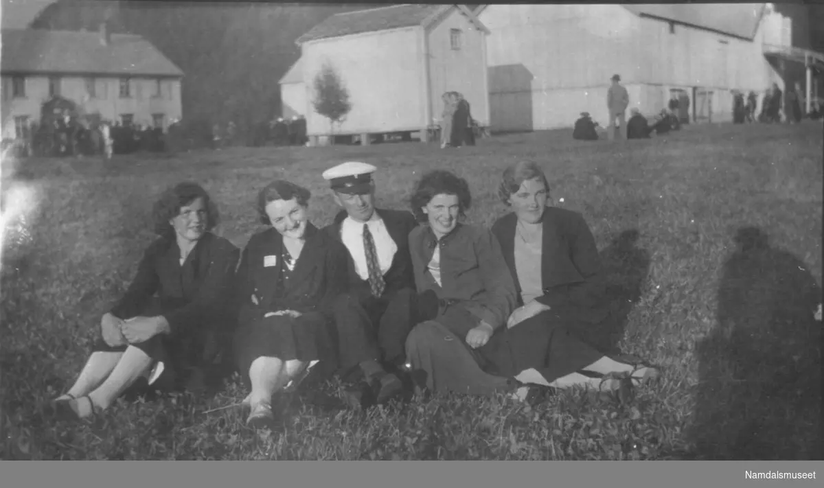 Fire kvinner og en mann i gresset.