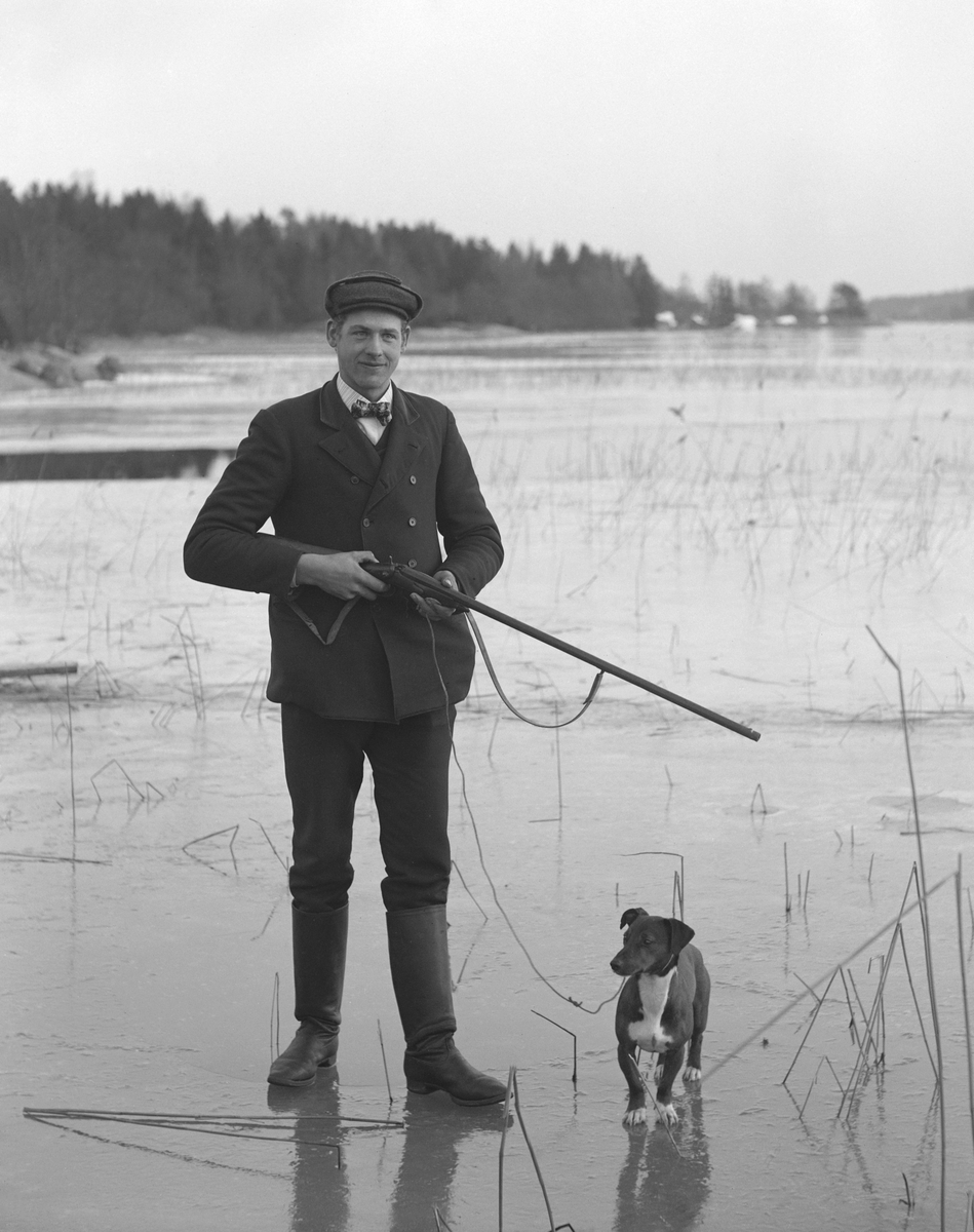 Arrendator Karl Karlsson från Mossen på Norra Finnö på besök med hunden Chasse hemma hos fotograf Emil Durling i Strömmen, Sankt Anna. Året är 1913.