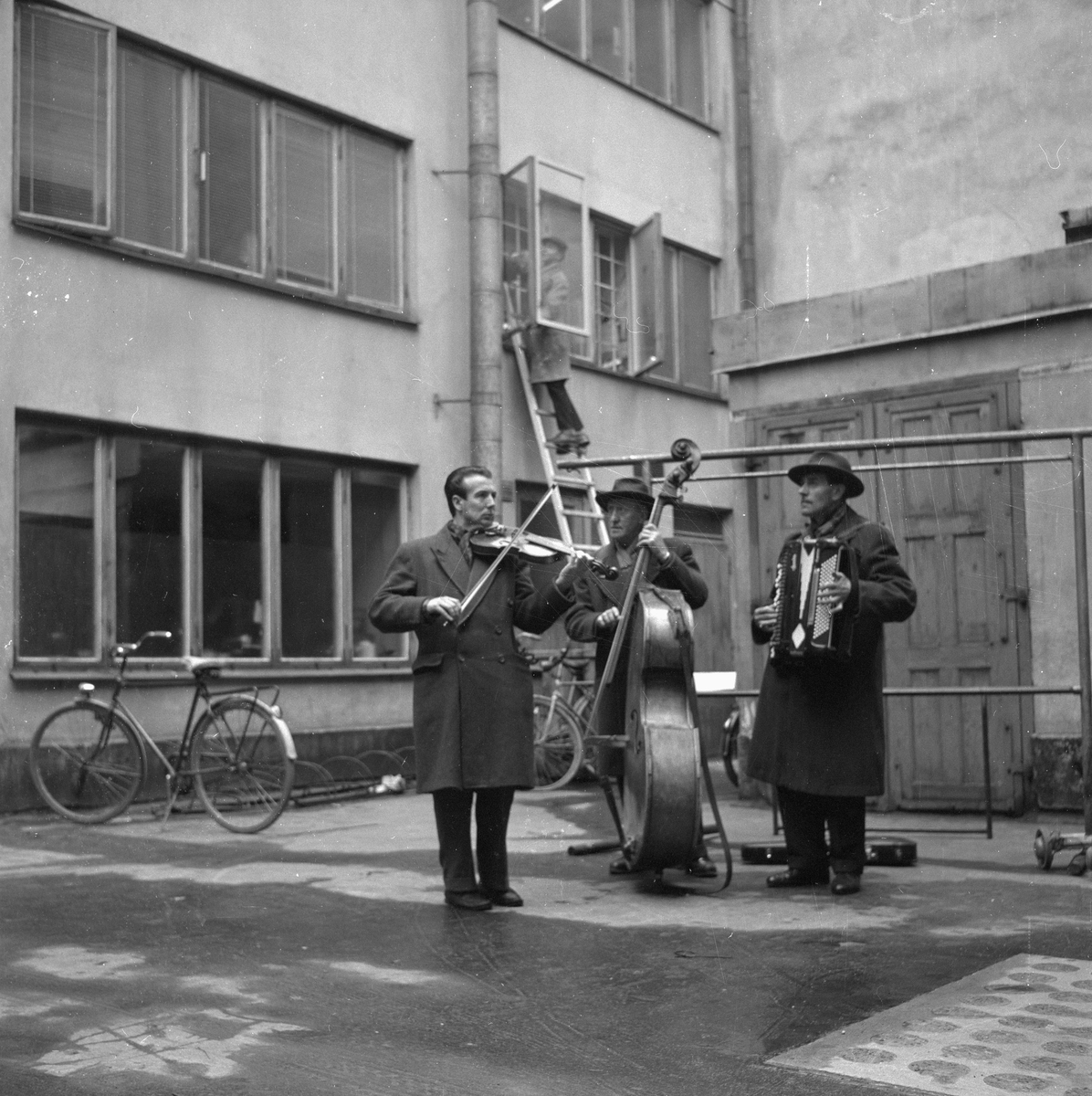 Gårdsmusikanter.
10 april 1959. 
Musikanterna är från Stockholm och spelar på en bakgård i Örebro. Rune Lövkvist fiol, Nils Olsson kontrabas och Tore Olsson dragspel.