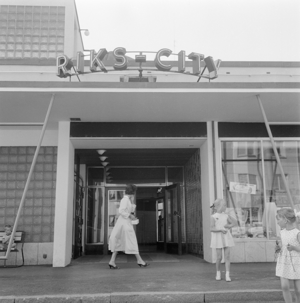 Centrumbildningen Riks-City i Norrköping, en stad i staden, växte fram under senare delen av 1950-talet. Höga bostadshus som fylldes med ljus och luft och gav plats för grönska, med samhällsservice in på knutarna och socialt hållbara strukturer, var en viktig komponent i decenniets folkhemsbygge. Bilden visar entrén till själva stadsdelscentrumet.