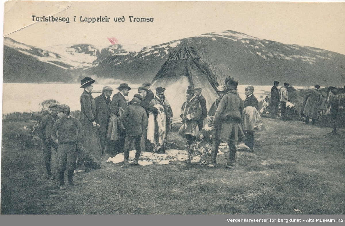En folkegruppe som besøker en samisk leir. Fjell og fjord i bakgrunnen.