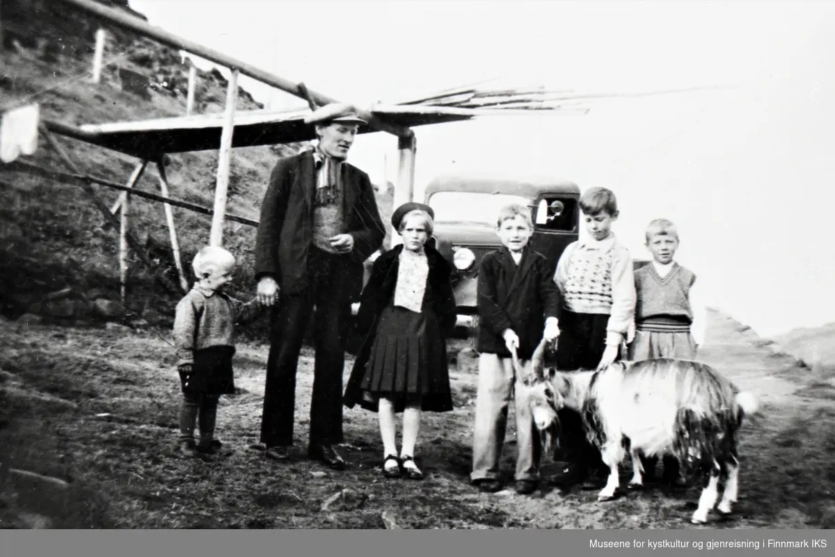 Honningsvåg, Storbukt. Gruppebilde med geit. I bakgrunnen Johan Edvardsens lastebil. Ca. 1936.