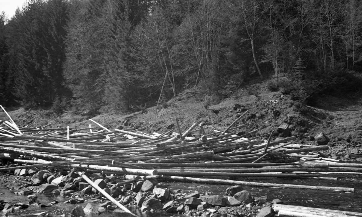 Tømmervase i Norderåa, ei sideelv som renner inn i Glomma fra vest i Elverum i Hedmark. Fotografiet oppgis å være tatt «nedenfor veibroen», antakelig den brua der Vestsivegen krysser vassdraget. Her var det en ikke ubetydelig mengde tømmer som var stuvet sammen i og langs et nesten tørrlagt elvefar. Bildet ble tatt våren 1944.