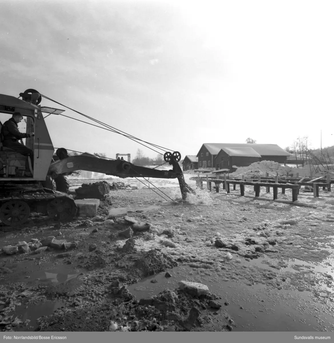 Borrning och grävmaskiner på isen i Tynderösundet. Troligen förbereds bygget av nya bron till Åstön. I bakgrunden på första bilden syns den gamla bron.