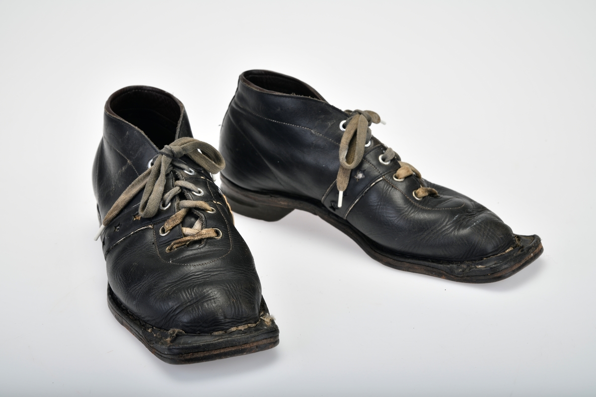 Et par beksømstøvler i størrelse 42 brukt som skisko og tursko. Skoene har randsydde lærsåler og gummihæler. Foran er de firkantet for feste i skibinding, og på undersiden er det tre hull til feste i skibinding. Det er skrudd på slitejern ved hullene. Bak på hælen er det spor til kandaharbinding. I front har skoene 5 par maljer for å snøre skolissene i. Skolissene er grå (opprinnelig hvite) bomullslissser med dekor i hvitt og rødt. Skoene har tunge under snøringen. På hver side av skoen er det skåret ut tre stjerner som dekor.