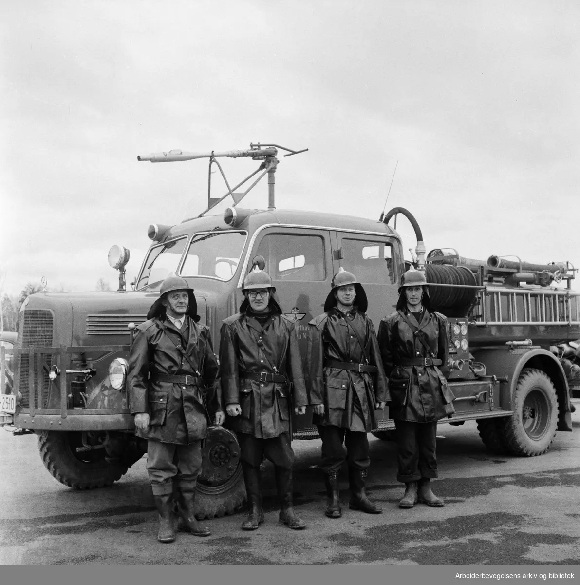 Brannmenn foran brannbil. Muligens brann og redningsberedskapen på Fornebu. November 1956.