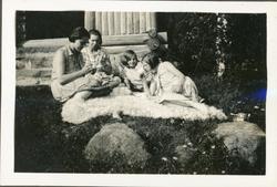 Fire jenter har piknik foran hytta. Ingelsrudsjøen. Trolig 1