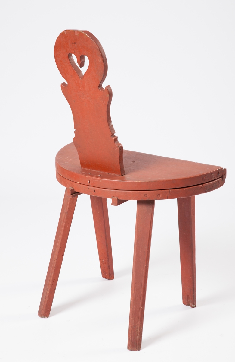 Bordstol med rund, hopfällbar skiva och fyra ben. Ryggstödet med profilerade kanter, hjärta utskuret mitt i. På ryggstödet märkt "NIS". Rödmålad.