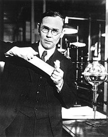 Bildet viser en mann med briller som jobber i en lab. Han holder frem en nylonstrømpe.