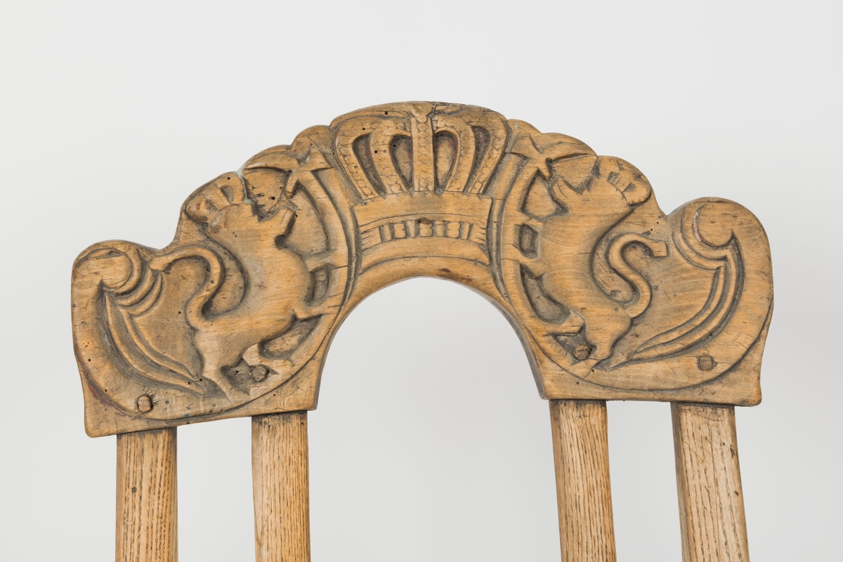 Toppstykket har skåret dekor av to løver med hellebard, som flankerer en krone i relieff.