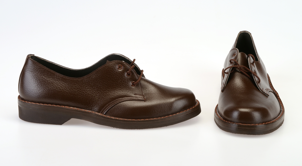 Et par barnesko i størrelse 38 i skoeske med silkepapir. Skoene er i mørkt brunt skinn med såler av svart gummi. Yttersålen har rutemønster og buet mønster. Ved hælen står det "Bever" i sålen. Skoene er randsydde med lysere brun tråd. I front er det 3 par hull med maljer for snøring. Under snøringen er det en enkel tunge av mørkt brunt skinn. Skoene har brune, runde skolisser. Skoene har innersåle av lær. De er foret med hvit tekstil i den fremre delen og grått lær (eller kunstlær?) i den bakre delen. Skoene ligger i en skoeske av papp som er stiftet sammen. På den ene kortsiden er det trykt på fabrikkens navn, varemerke og logo samt artikkelnummer og størrelse. Logoen er en sirkel med en Nord-pil igjennom. Logo og tekst er i rødt med påstemplet artikkelnummer og påskrevet størrelse i svart. Skoene er ikke brukt.