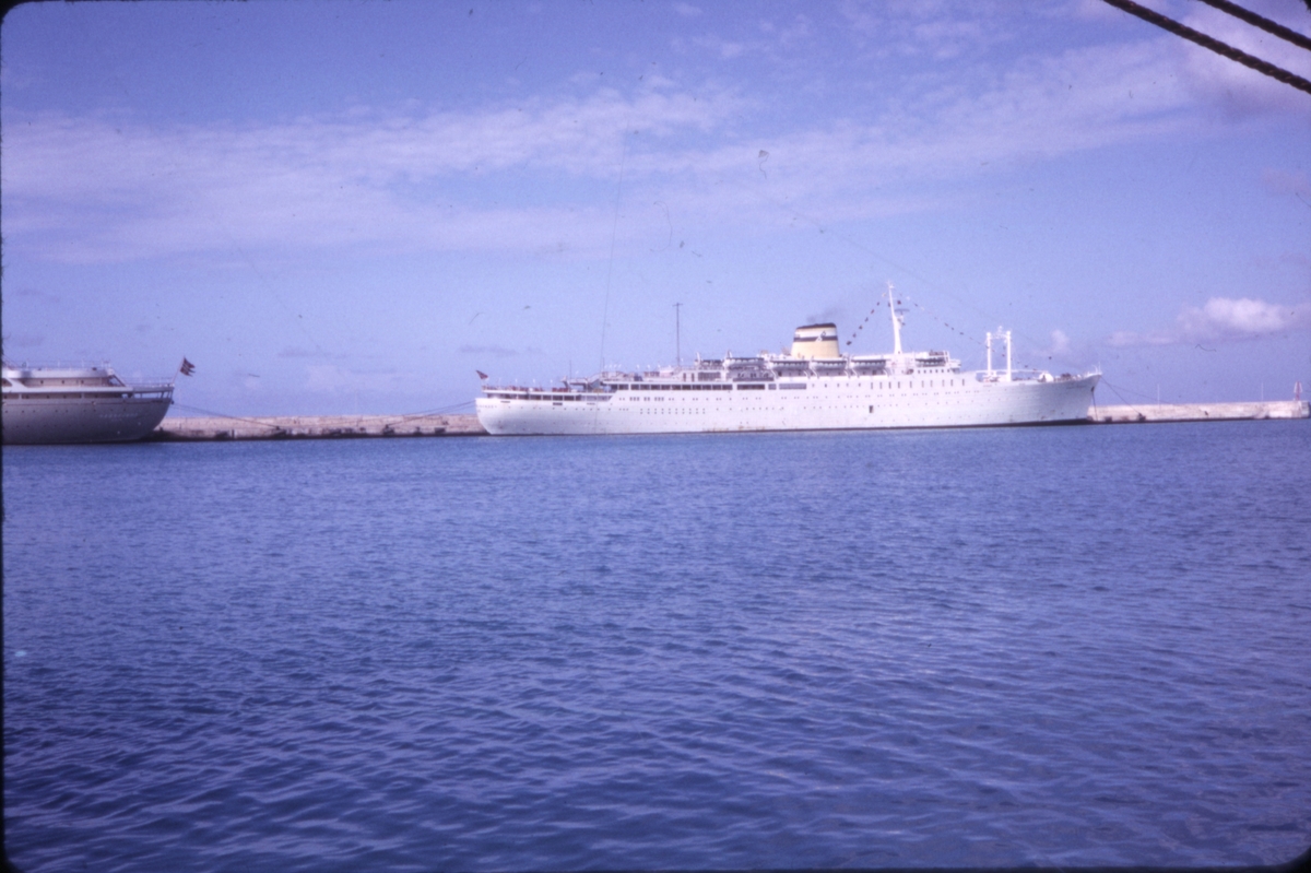 Ukjent cruiseskip ligger til kai, med akterenden av 'M/S Sagafjord' synlig til venstre. 'Sagafjord' Christmas Holiday Cruise 1965.