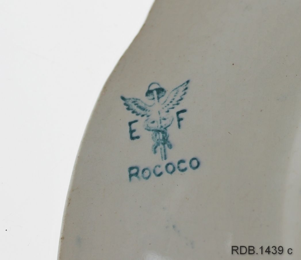 Dyp tallerken med mønsteret Rococo i blått på kvit bunn. En sprekk i sida. Fabrikkstempel under.