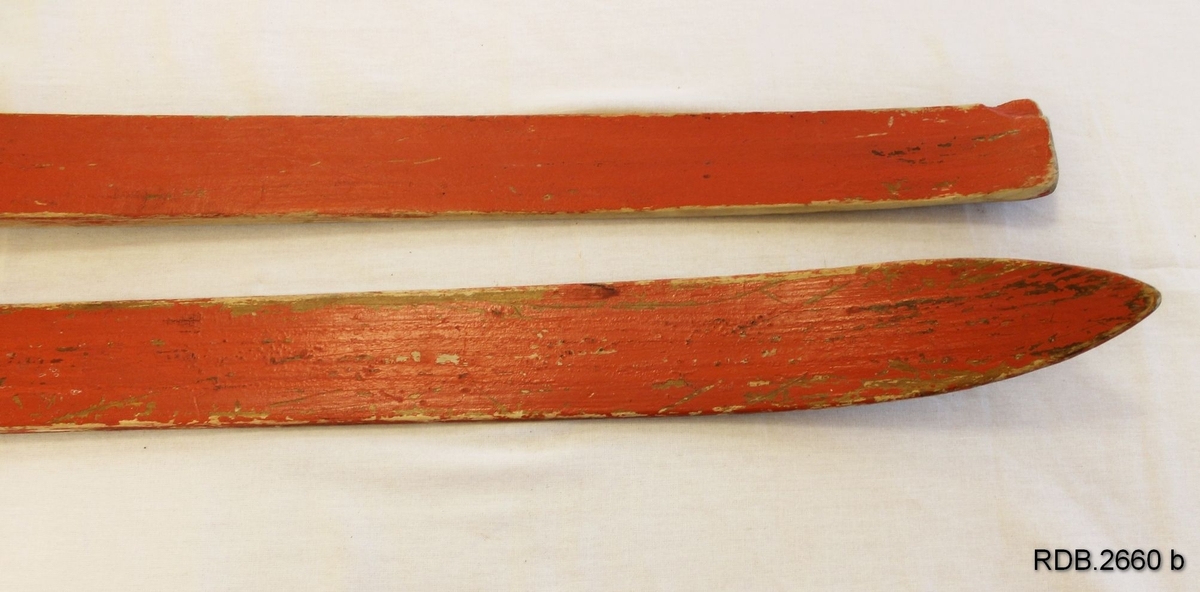 Et par rødmalte, jevnbrede helvedski uten bindinger. Lav skibrett. Malinga er ikke primær og er avslitt, På fotsteget er det 4 hull etter binding og flere stifter etter fotplate som er fjernet.