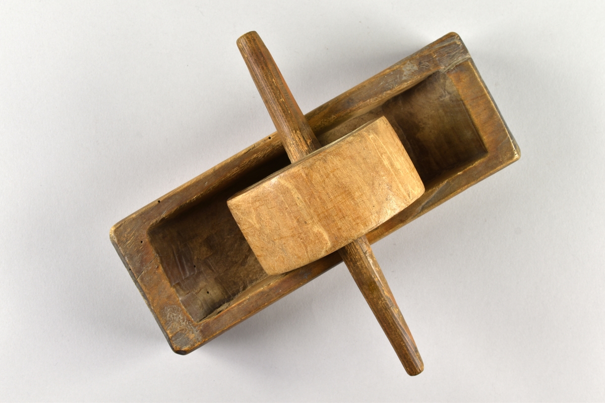 Kaffekvarn av trä. Består av ett rektangulärt urkarvat tråg och en rulle (malhjul). I mitten på rullen en pinne.