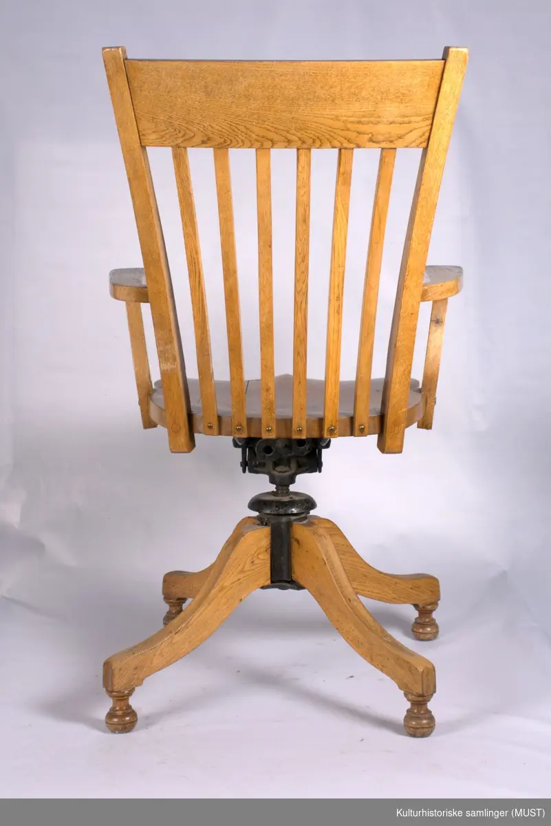 Svingstol med fire ben. Laget av eik. Spiler i ryggen og armlene.
