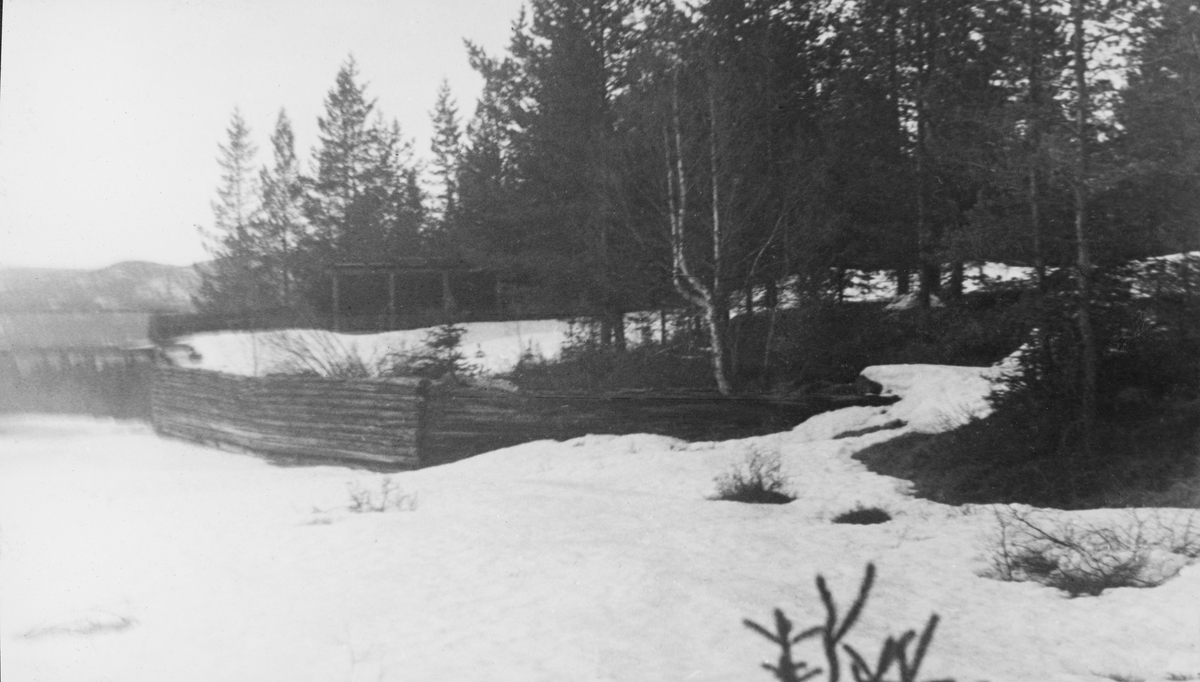 Fiskvikrokkdalsdammen i elva Rokka i Rendalen, fotografert på en seinvintersdag i 1943. Landskapet og vassdraget var ennå dekt av snø. Vi ser imidlertid skådammen som ledet inn mot den vestre damløpet, en loddrett tømmerskjerm. Vi aner også takoverbygget over den østre damarmen mot barskogen i bakgrunnen. Motivet inngår i et todelt opptak - jfr. SJF.1989-04650. Mer informasjon om denne fløtingsdammen finnes under fanen «Andre opplysninger».