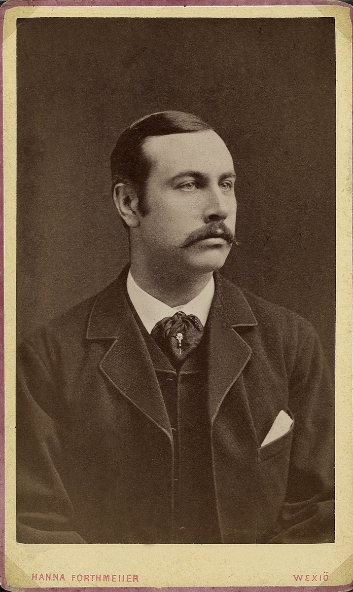 Porträttfoto av en man i kavajkostym med väst, stärkkrage och slips med kråsnål. 
Bröstbild, halvprofil. Ateljéfoto.