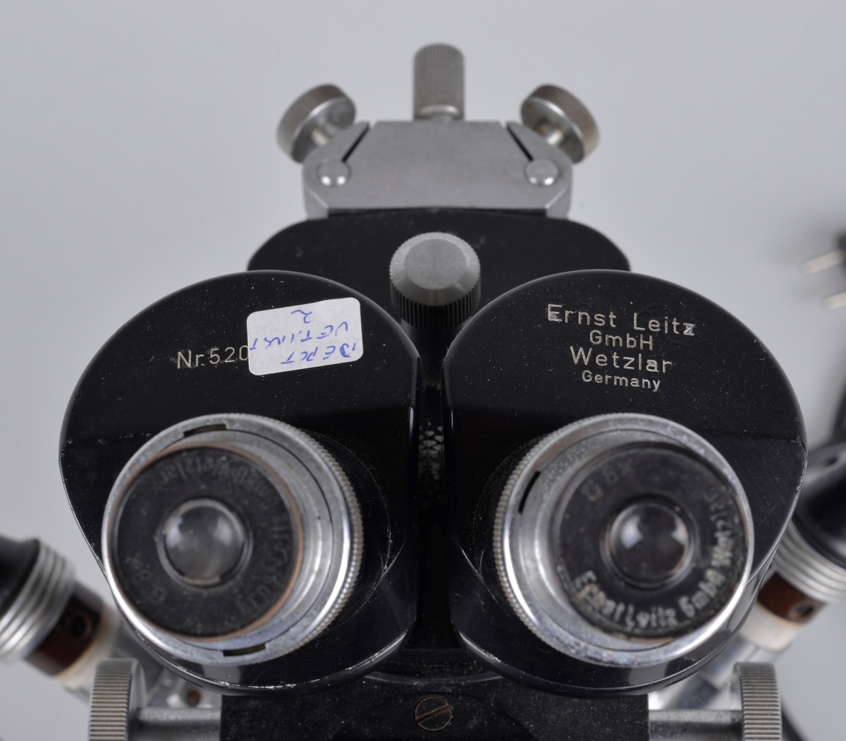 Binokulært mikroskop, har to okularer for bruk med begge øyne.
Apparatet er produsert i Tyskeland og brukt av Vetrinærinstituttets fagfolk. 

Chassiet er muligens laget i stål, svartlakkert.