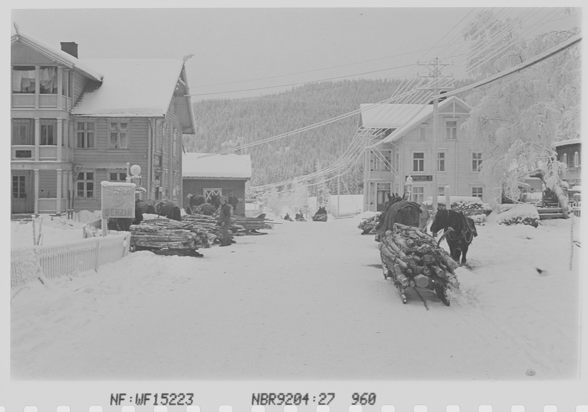 Tømmertransport med hest og slede i tettbebyggelse vinterstid. Fotografert 1942.