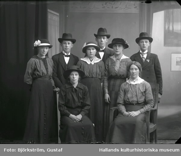 Ateljéfoto av åtta ungdomar, fem flickor och tre pojkar som alla utom en bär hatt. Beställare: Karl Andersson.