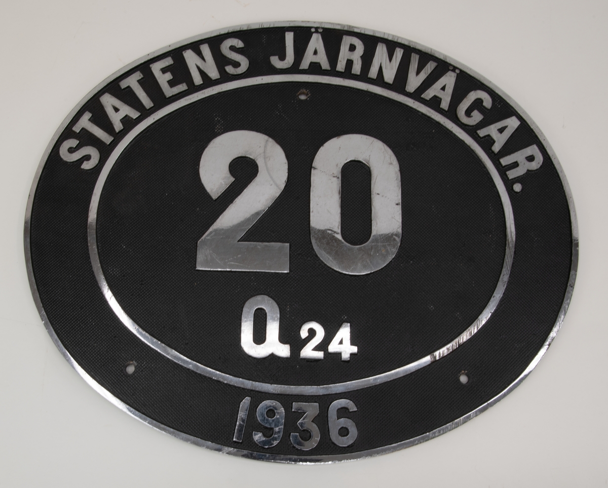Nummerskylt för omformare Statens Järnvägar Q24 nr 20. Oval, gjuten skylt med svartmålad botten. Tre skruvhål.