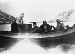 Fire personer i en båt. Fjord og fjell i bakgrunnen.