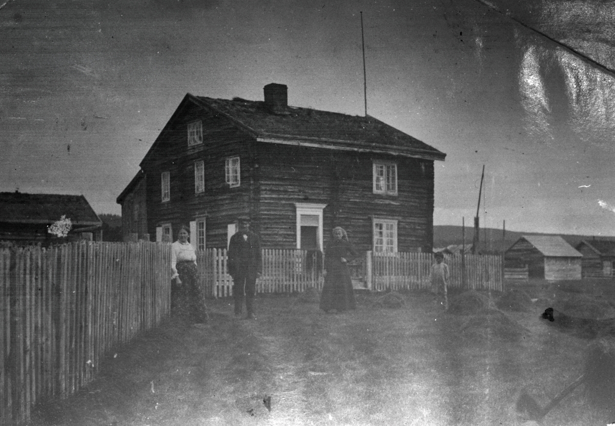 Motiv av to kvinner og en mann som står fremfor et bolighus. Herr og fru Knoblok til venstre i bildet. Kvinnen til høyre heter Regine.