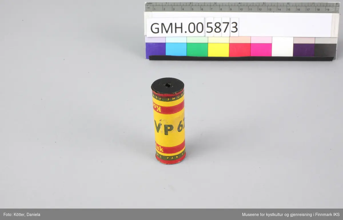 Dette er en filmrull på en metallspole. Selve filmmaterialet beskyttes av papir i gult, rødt og svart. Filmen er ubrukt.