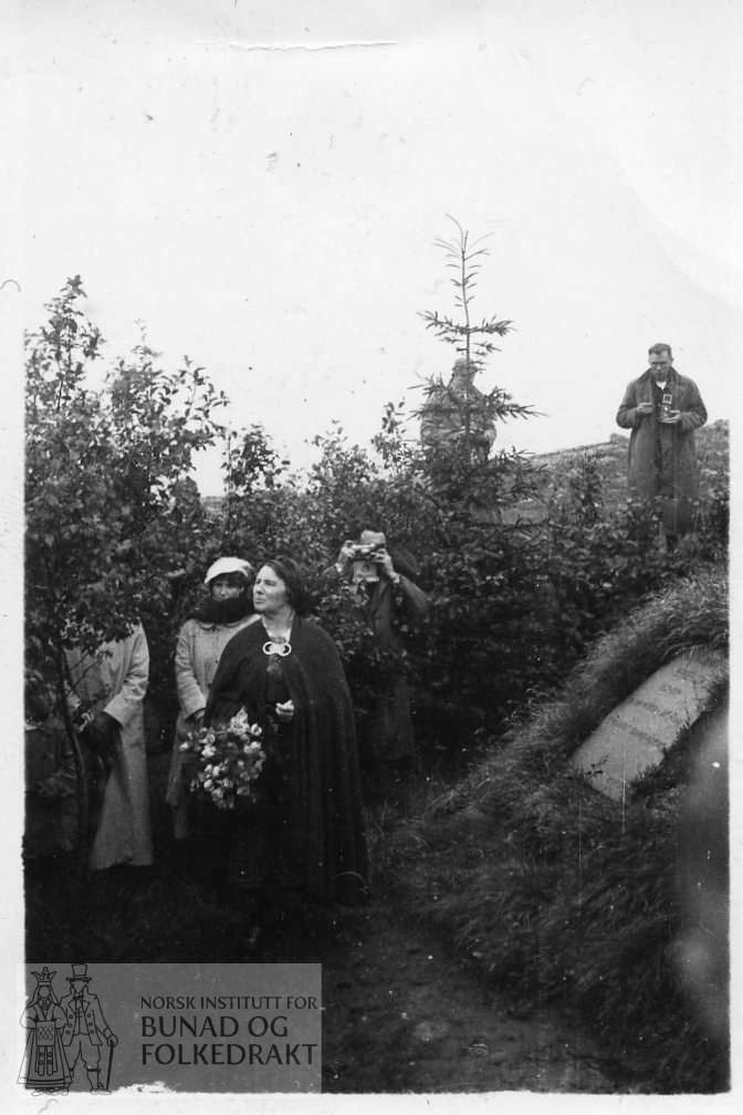 Klara Semb legg ned krans ved grava til Hulda Garborg. Klara Semb kledd i bunad, dei andre i motedrakt.
